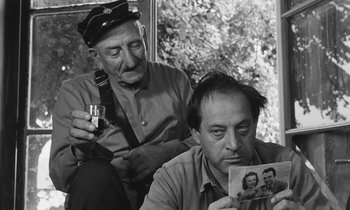 Movie still from “The Two of Us” (1967), directed by Claude Berri – Two men sitting next to each other and one is holding up a picture; Close Up shot, Over the shoulder angle