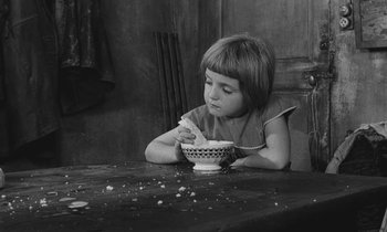 Movie still from “The Two of Us” (1967), directed by Claude Berri – A little girl sitting at a table with a bowl of cereal; Medium shot, High angle