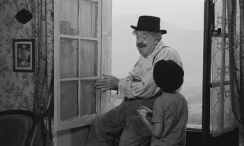 Movie still from “The Two of Us” (1967), directed by Claude Berri – An old man sitting on a window ledge with a young boy; Medium shot, Low angle