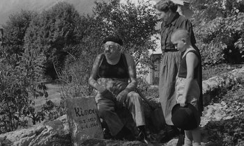 Movie still from “The Two of Us” (1967), directed by Claude Berri – An older man sitting on a rock next to a woman and a young boy; Wide shot, High angle