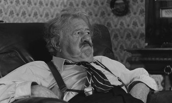 Movie still from “The Two of Us” (1967), directed by Claude Berri – An old man with a beard and a tie is sitting in a chair; Close Up shot, High angle
