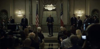 Movie still from “House of Cards” (2013), created by Beau Willimon – A man standing in front of an audience; Wide shot, Low angle