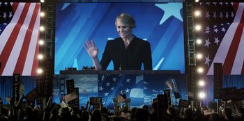 Movie still from “House of Cards” (2013), created by Beau Willimon – A woman is giving a speech at a political event; Medium shot, Low angle