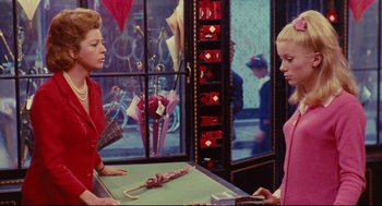 Movie still from “The Umbrellas of Cherbourg” (1964), directed by Jacques Demy – Two women are standing in front of an umbrella; Medium shot, Over the shoulder angle