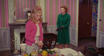 Movie still from “The Umbrellas of Cherbourg” (1964), directed by Jacques Demy – Two women standing in front of a dining room table; Medium shot, Over the shoulder angle