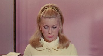 Movie still from “The Umbrellas of Cherbourg” (1964), directed by Jacques Demy – A young woman with blonde hair wearing a white jacket; Close Up shot, Low angle