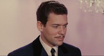 Movie still from “The Umbrellas of Cherbourg” (1964), directed by Jacques Demy – A person wearing a suit and tie; Close Up shot, Low angle