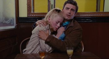 Movie still from “The Umbrellas of Cherbourg” (1964), directed by Jacques Demy – A man and a woman sitting at a table with drinks; Medium shot, High angle