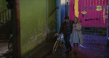 Movie still from “The Umbrellas of Cherbourg” (1964), directed by Jacques Demy – A man and a woman standing next to a bicycle; Wide shot, High angle