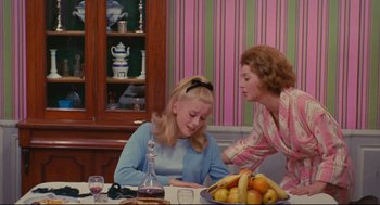 Movie still from “The Umbrellas of Cherbourg” (1964), directed by Jacques Demy – Two women sitting at a table with a bowl of fruit; Medium shot, High angle