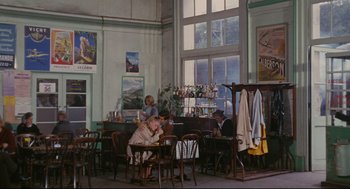 Movie still from “The Umbrellas of Cherbourg” (1964), directed by Jacques Demy – People are sitting at tables in an old fashioned restaurant; Wide shot, High angle