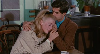 Movie still from “The Umbrellas of Cherbourg” (1964), directed by Jacques Demy – A man and a woman sitting at a wooden table; Medium shot, Over the shoulder angle