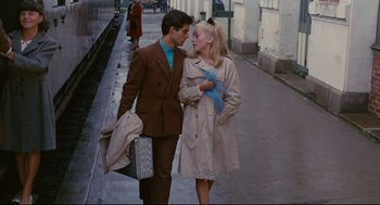 Movie still from “The Umbrellas of Cherbourg” (1964), directed by Jacques Demy – A man and a woman standing next to each other on the sidewalk; Medium shot, High angle