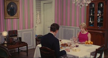 Movie still from “The Umbrellas of Cherbourg” (1964), directed by Jacques Demy – A man and a woman sitting at a dinner table; Wide shot, High angle