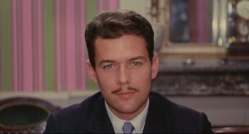 Movie still from “The Umbrellas of Cherbourg” (1964), directed by Jacques Demy – A person wearing a suit and tie; Close Up shot, High angle