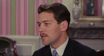 Movie still from “The Umbrellas of Cherbourg” (1964), directed by Jacques Demy – A person wearing a suit and tie; Close Up shot, High angle