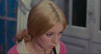 Movie still from “The Umbrellas of Cherbourg” (1964), directed by Jacques Demy – A person with a pen in her mouth; Close Up shot, High angle