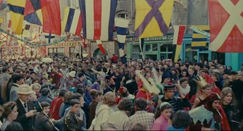 Movie still from “The Umbrellas of Cherbourg” (1964), directed by Jacques Demy – A crowd of people standing in front of a building; Extreme Wide shot, High angle