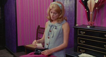 Movie still from “The Umbrellas of Cherbourg” (1964), directed by Jacques Demy – A woman in a blue dress holding a piece of paper; Medium shot, High angle