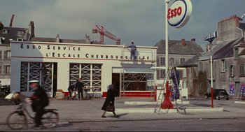 Movie still from “The Umbrellas of Cherbourg” (1964), directed by Jacques Demy – A group of people working on a building; Extreme Wide shot, Low angle