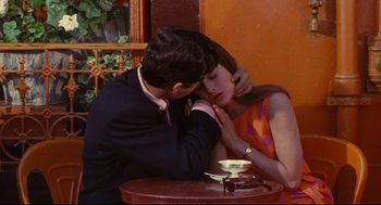 Movie still from “The Umbrellas of Cherbourg” (1964), directed by Jacques Demy – A man and a woman sitting at a table with a cup of coffee; Medium shot, High angle