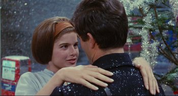 Movie still from “The Umbrellas of Cherbourg” (1964), directed by Jacques Demy – A man and a woman are hugging each other; Close Up shot, Over the shoulder angle