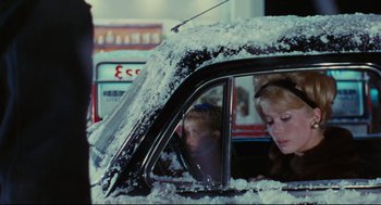 Movie still from “The Umbrellas of Cherbourg” (1964), directed by Jacques Demy – A woman sitting in a car with a child in the passenger seat; Close Up shot, Over the shoulder angle