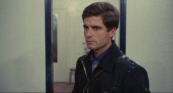 Movie still from “The Umbrellas of Cherbourg” (1964), directed by Jacques Demy – A man in a black jacket standing next to a door way; Close Up shot, Over the shoulder angle