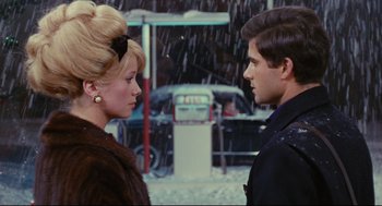 Movie still from “The Umbrellas of Cherbourg” (1964), directed by Jacques Demy – A man and a woman standing next to each other in the snow; Close Up shot, Over the shoulder angle