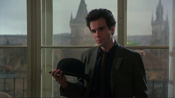 Movie still from “The Unbearable Lightness of Being” (1988), directed by Philip Kaufman – A man in a suit and tie holding a hat; Close Up shot, Over the shoulder angle