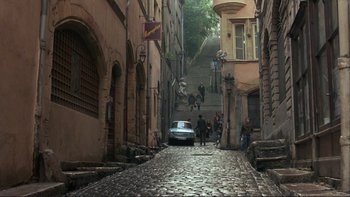 Movie still from “The Unbearable Lightness of Being” (1988), directed by Philip Kaufman – A car is parked on the side of the street; Extreme Wide shot, High angle