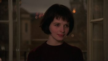 Movie still from “The Unbearable Lightness of Being” (1988), directed by Philip Kaufman – A woman with short black hair is smiling for the camera; Close Up shot, High angle