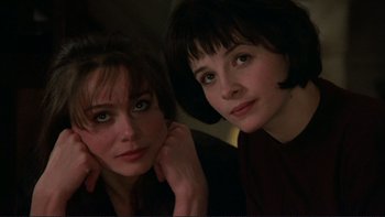 Movie still from “The Unbearable Lightness of Being” (1988), directed by Philip Kaufman – Two young women posing for a picture in a dark room; Close Up shot, High angle