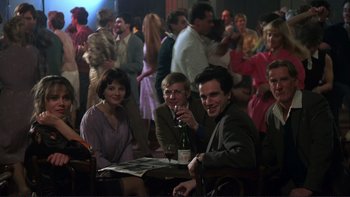 Movie still from “The Unbearable Lightness of Being” (1988), directed by Philip Kaufman – A group of people sitting at a table drinking wine; Medium shot, Over the shoulder angle