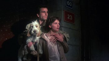 Movie still from “The Unbearable Lightness of Being” (1988), directed by Philip Kaufman – A man and a woman with a dog in front of a building; Medium shot, Low angle