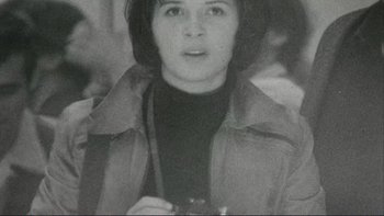 Movie still from “The Unbearable Lightness of Being” (1988), directed by Philip Kaufman – An old black and white photo of a woman holding a camera; Close Up shot, High angle