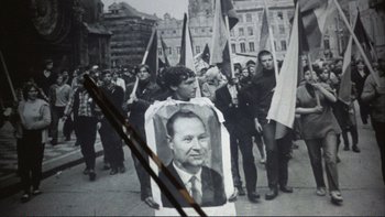 Movie still from “The Unbearable Lightness of Being” (1988), directed by Philip Kaufman – A group of people marching down a street holding flags; Medium shot, High angle