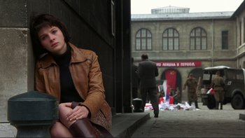 Movie still from “The Unbearable Lightness of Being” (1988), directed by Philip Kaufman – A woman sitting on the side of the street; Medium shot, Low angle