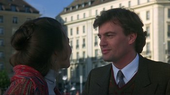 Movie still from “The Unbearable Lightness of Being” (1988), directed by Philip Kaufman – A man and a woman standing next to each other in front of a building; Close Up shot, Over the shoulder angle