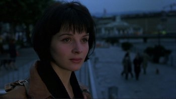 Movie still from “The Unbearable Lightness of Being” (1988), directed by Philip Kaufman – A person wearing a jacket near a building; Close Up shot, Over the shoulder angle