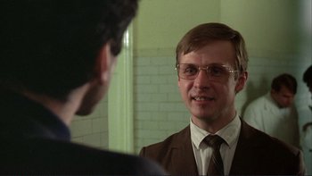 Movie still from “The Unbearable Lightness of Being” (1988), directed by Philip Kaufman – A man in a suit and tie talking to another man in a suit and tie in front of a bathroom mirror; Close Up shot, Over the shoulder angle