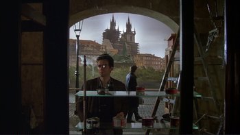 Movie still from “The Unbearable Lightness of Being” (1988), directed by Philip Kaufman – A man standing in front of a window with a castle in the background; Wide shot, Over the shoulder angle