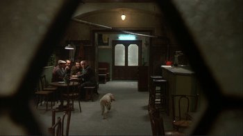 Movie still from “The Unbearable Lightness of Being” (1988), directed by Philip Kaufman – A group of people and a dog in a room; Wide shot, High angle