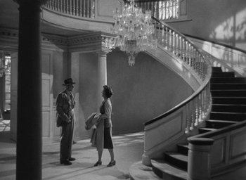 Movie still from “The Uninvited” (1944), directed by Lewis Allen – A man and a woman are standing in front of a staircase; Wide shot, High angle