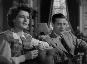 Movie still from “The Uninvited” (1944), directed by Lewis Allen – A man and a woman sitting next to each other holding wine glasses; Medium shot, Low angle
