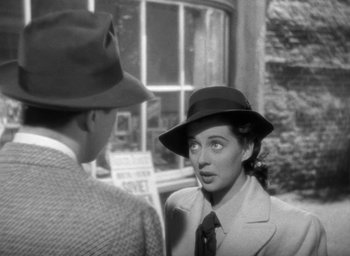 Movie still from “The Uninvited” (1944), directed by Lewis Allen – A woman wearing a suit and a hat talking to a man in front of a building; Close Up shot, High angle