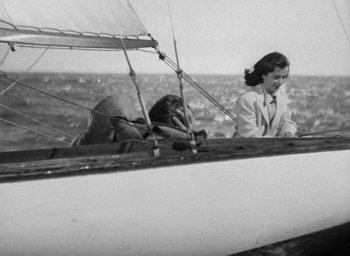 Movie still from “The Uninvited” (1944), directed by Lewis Allen – An old black and white photo of a woman on a sailboat; Wide shot, High angle