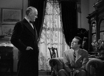 Movie still from “The Uninvited” (1944), directed by Lewis Allen – Two men in suits are talking in a living room; Medium shot, Over the shoulder angle