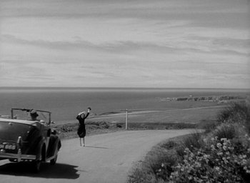 Movie still from “The Uninvited” (1944), directed by Lewis Allen – An old car driving down a road near the ocean; Extreme Wide shot, High angle