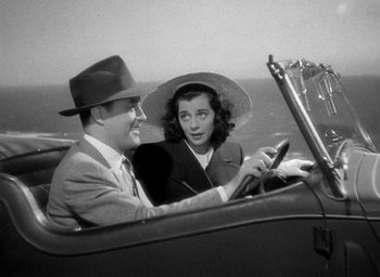 Movie still from “The Uninvited” (1944), directed by Lewis Allen – A man and a woman driving a car in the road; Medium shot, High angle